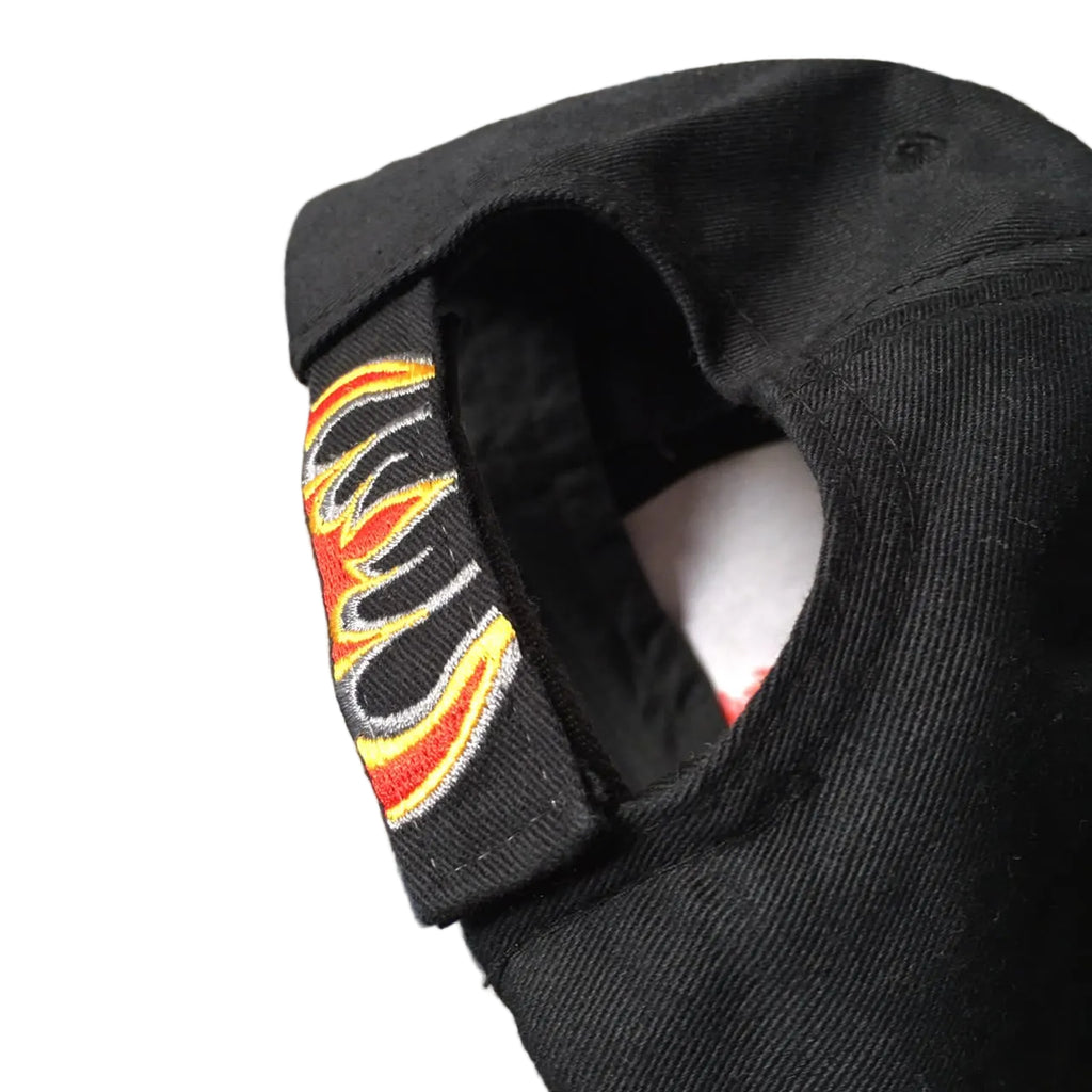 Close-up of the back strap and embroidered flame detail of a black baseball cap.
